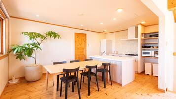 A modern kitchen with white cabinets, a central island, and a dining area with a table and chairs.