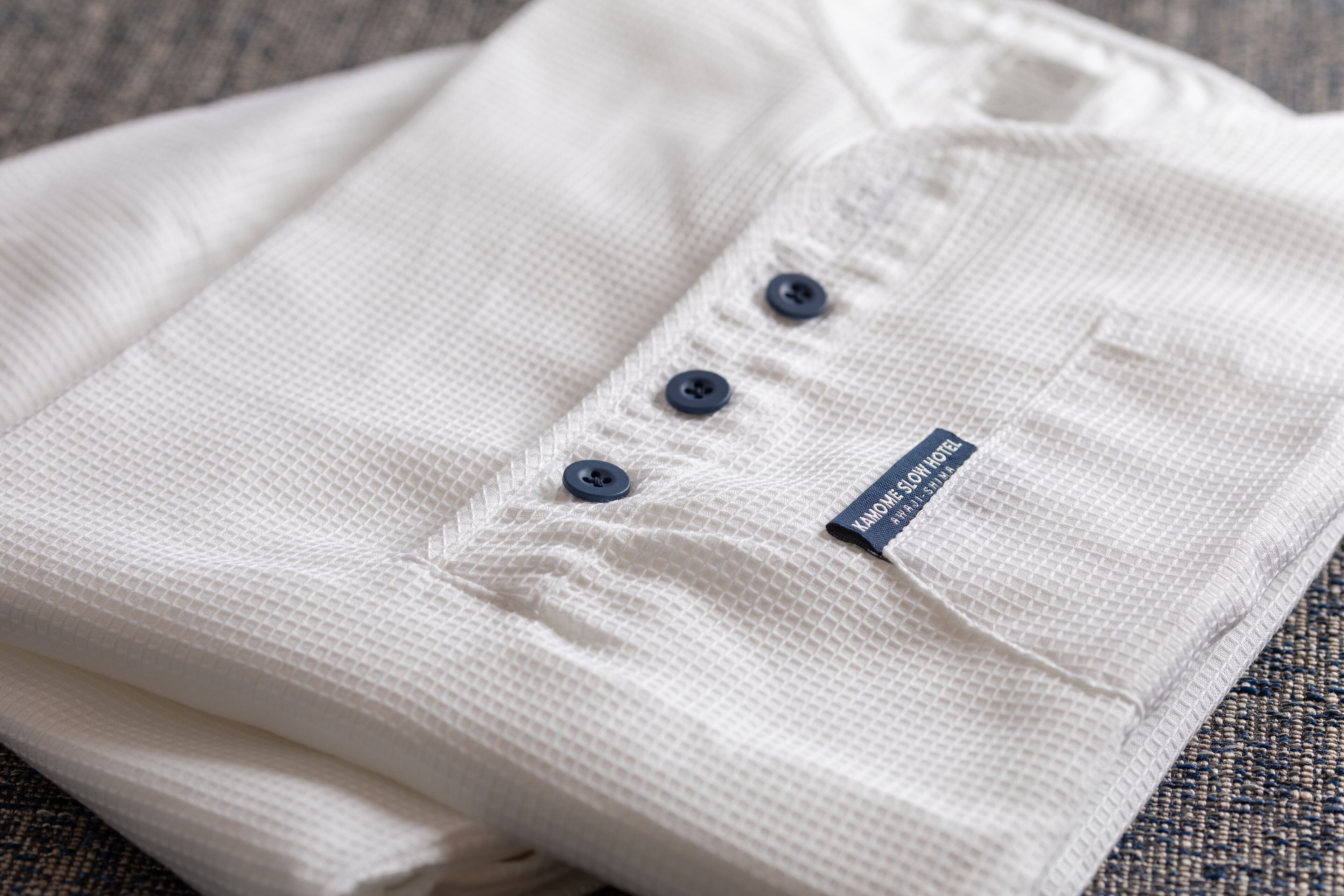 A neatly folded white shirt with a label and three buttons.