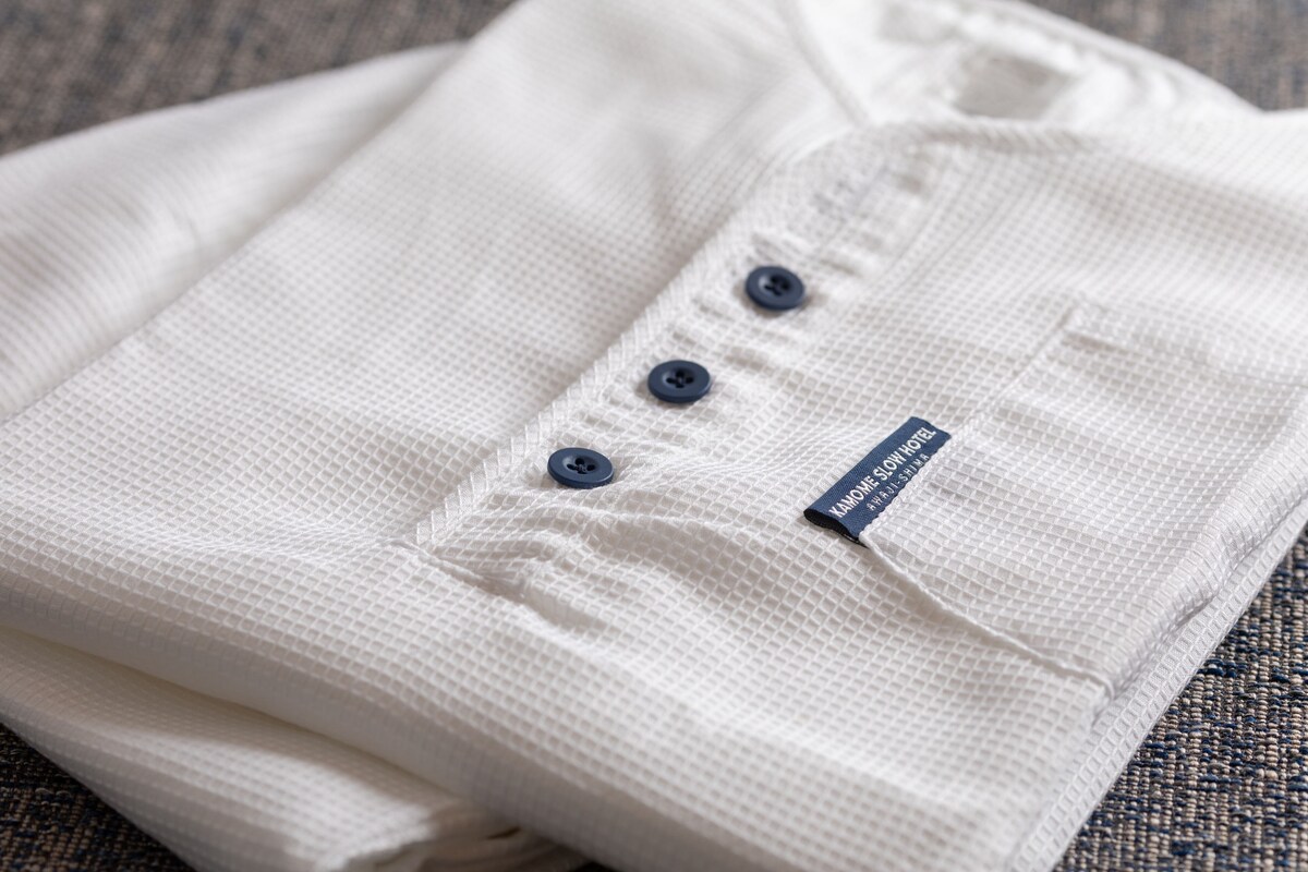A neatly folded white shirt with a label and three buttons.