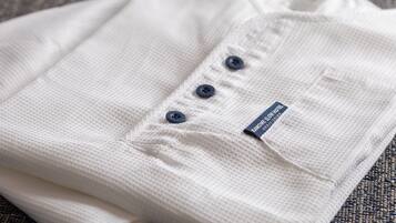 A neatly folded white shirt with a label and three buttons.
