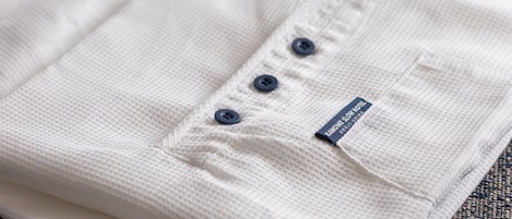 Una camisa blanca doblada con una etiqueta y tres botones.