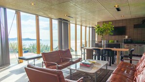 A modern living room with leather sofas, a coffee table, and a view of the sea. - Kamome Slow Hotel (Awaji)