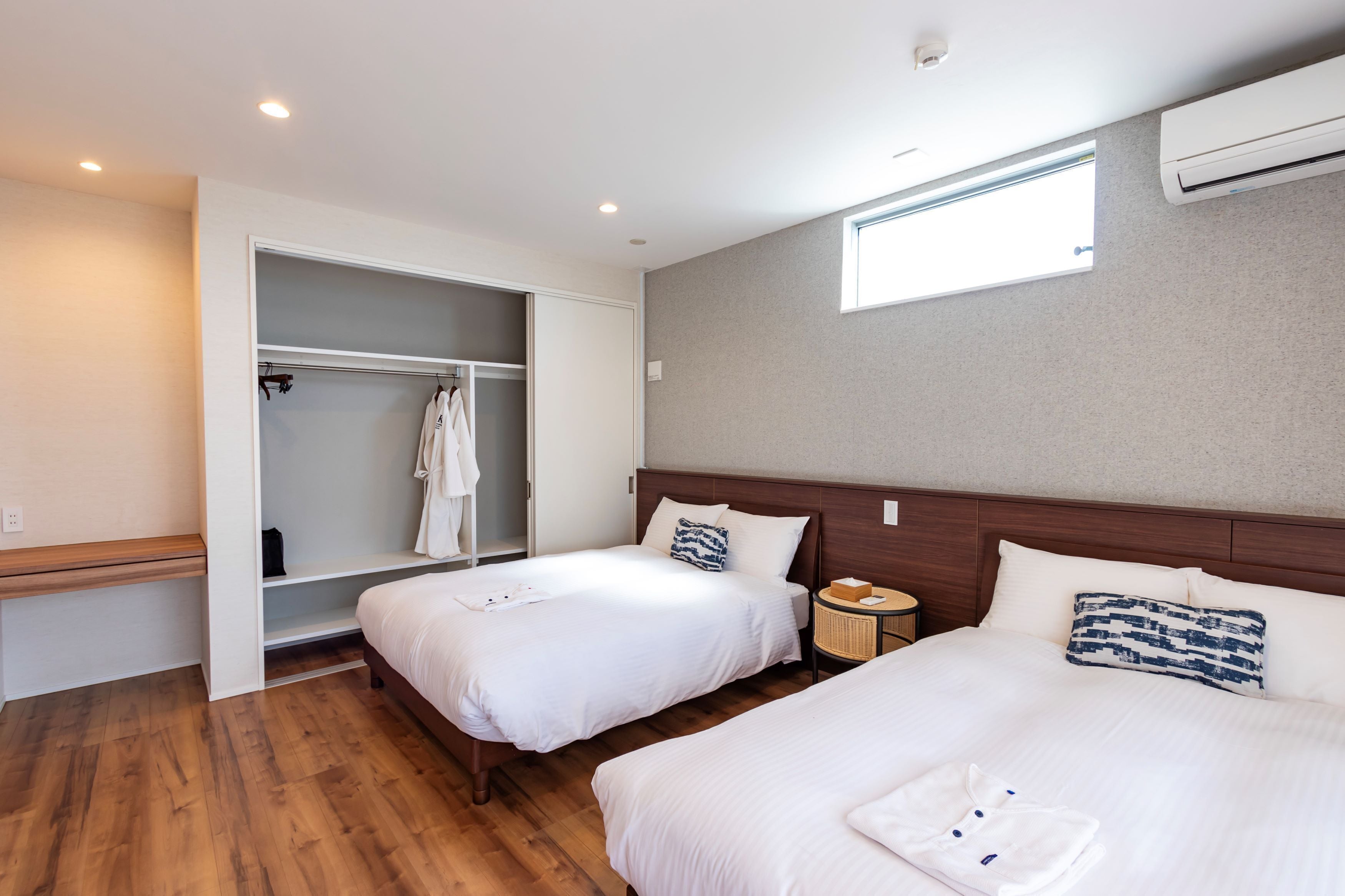 Une chambre d’hôtel avec deux lits, une armoire, une table de chevet et une fenêtre.