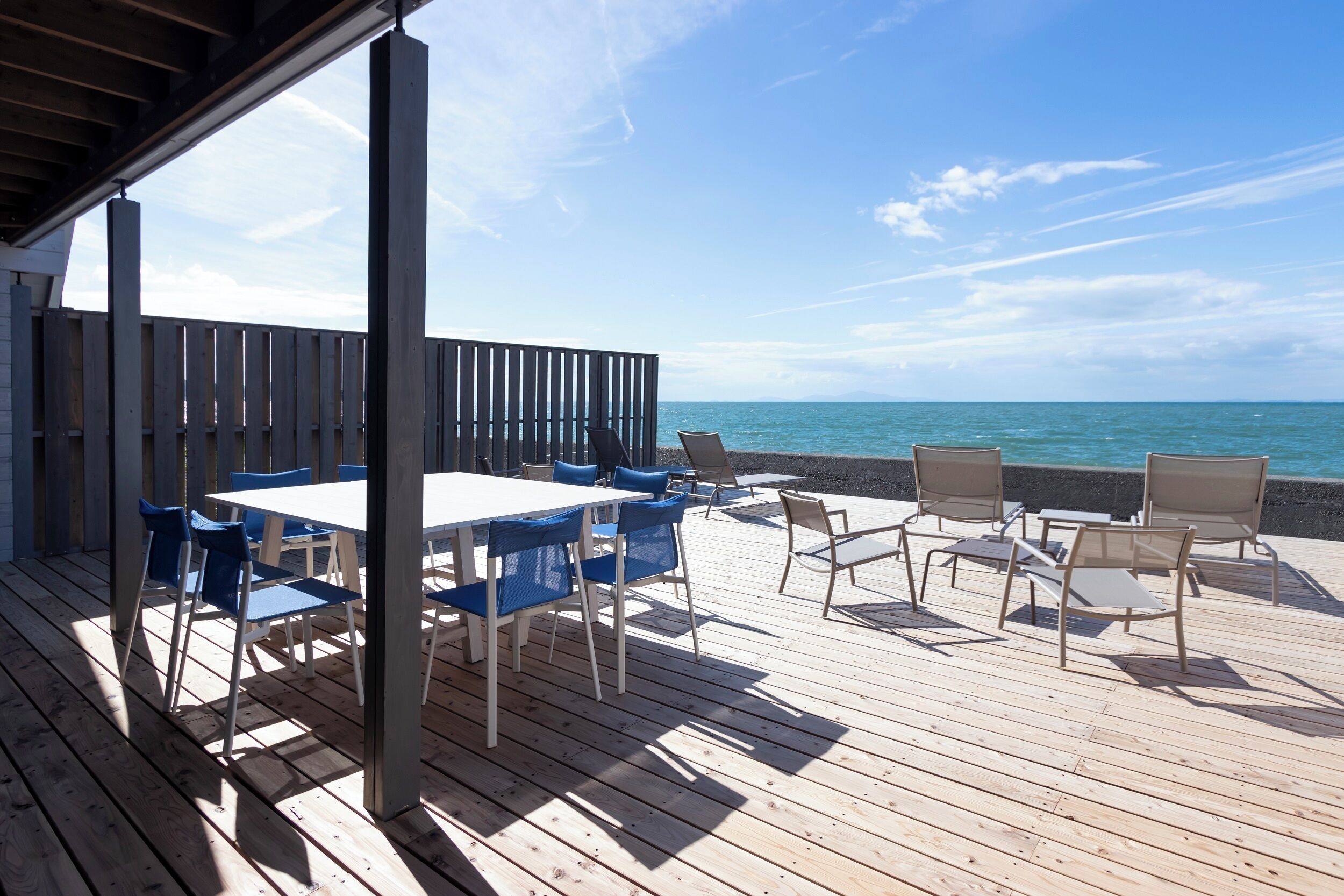 Une terrasse en bois avec une table et des chaises, donnant sur une plage.