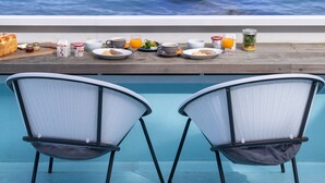 A dining table with breakfast items and two chairs facing a view of the ocean. - Kamome Slow Hotel (Awaji)