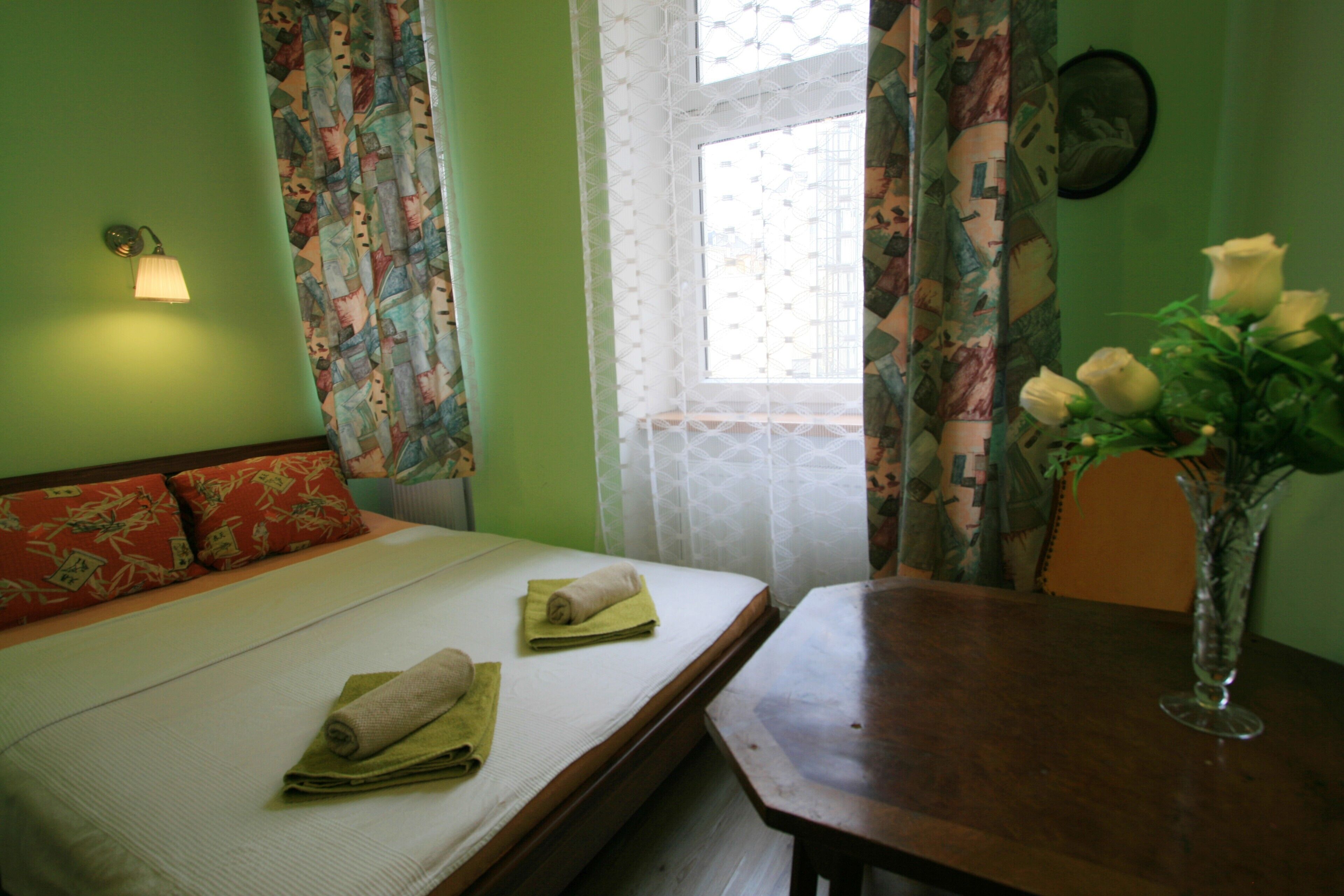 Ein Zimmer mit einem Bett, einem Tisch und einer Vase mit Blumen.