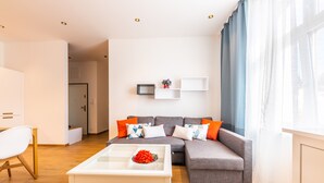 A modern living room with a grey sofa, white coffee table, and a small side table. - Victus Apartamenty - Malmo (Sopot)