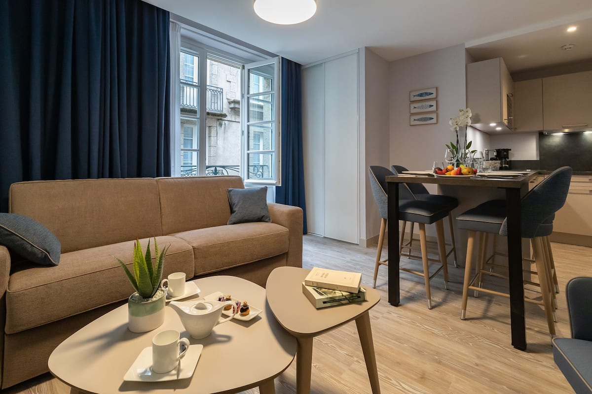 Een moderne woonkamer met een bank, salontafel en een eethoek met stoelen.