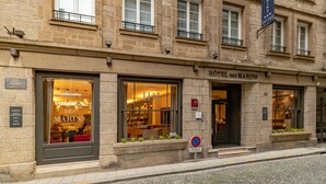 A hotel facade with multiple windows, a prominent sign for "HOTEL DES MARINS," and a no parking sign. - Appartement des Marins (Saint-Malo)
