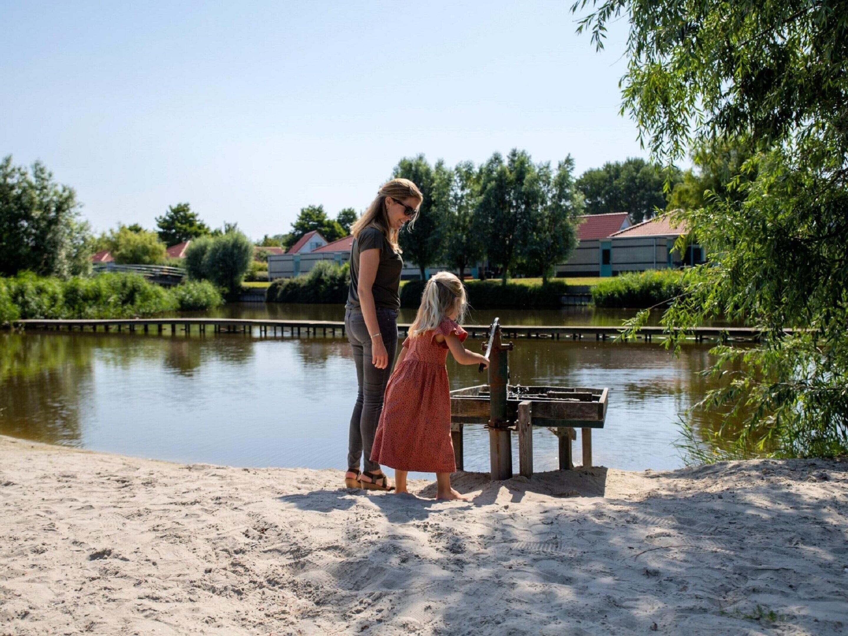 A sandy beach area with a water body and a wooden structure.