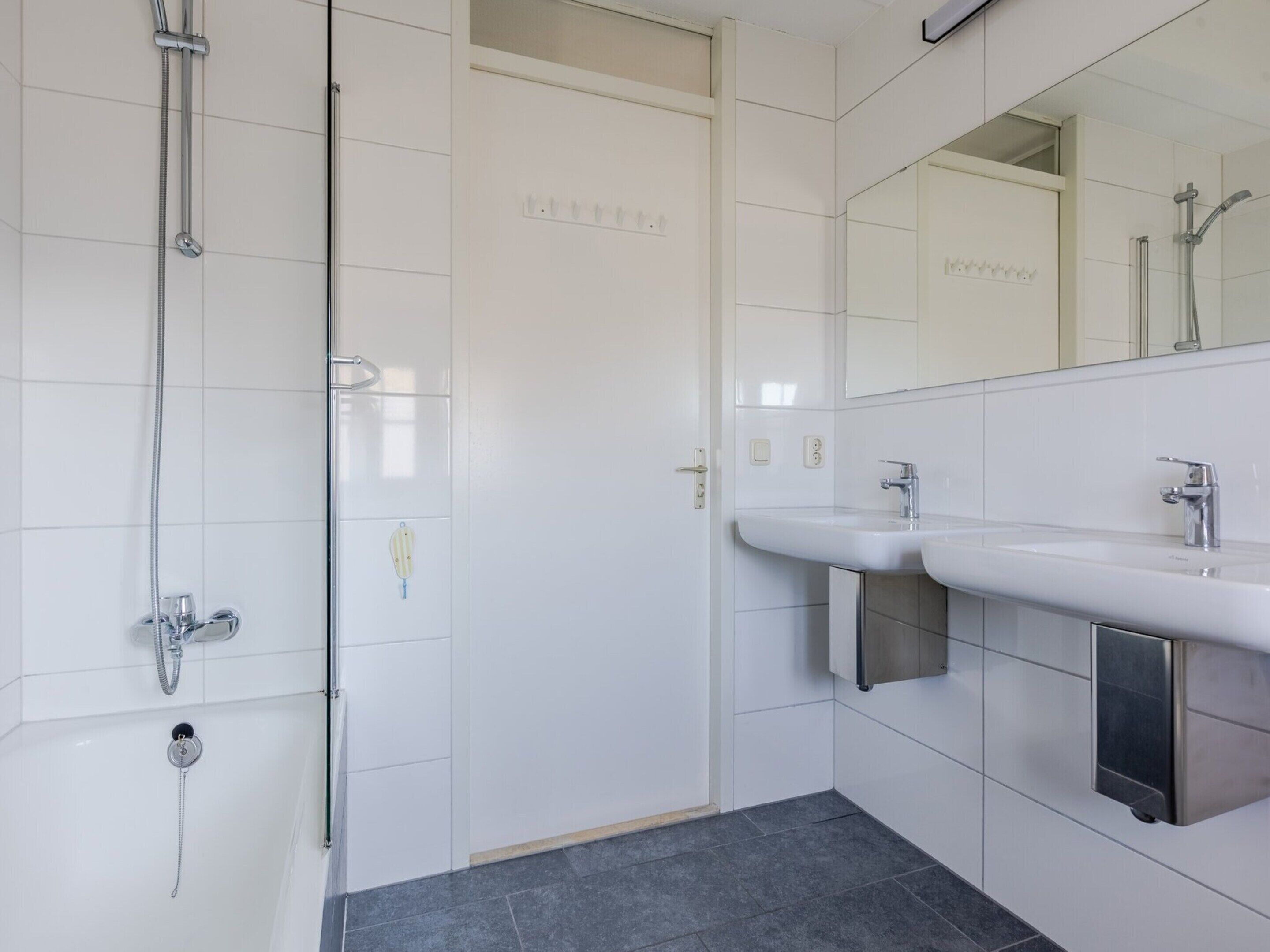 A modern bathroom with a glass shower enclosure, a white sink, and a mirror above the sink.