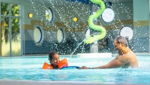 A swimming pool with a child and an adult, water splashing around. - Comfortable Bungalow With Dishwasher Near the Beach (Hollum)