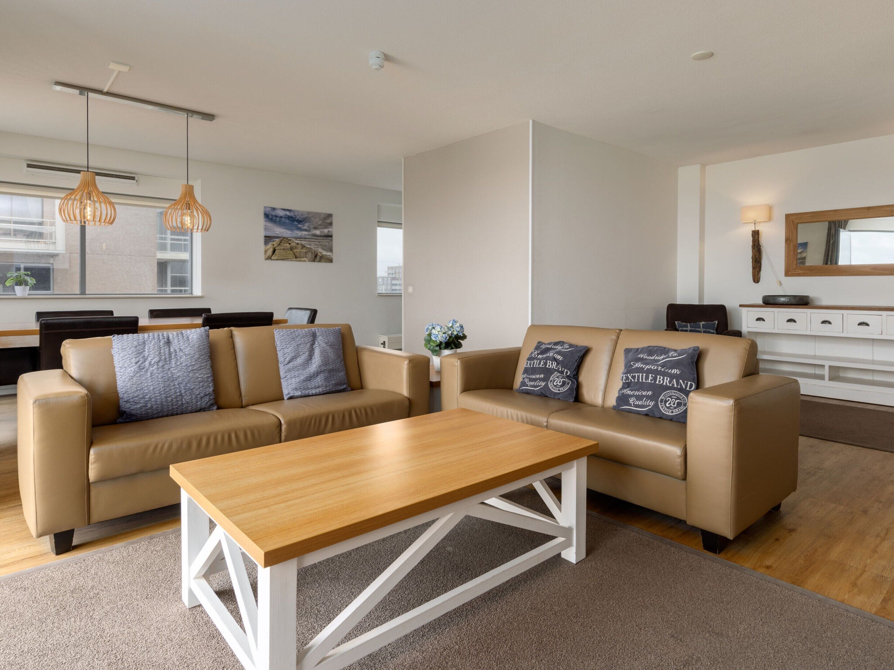 A modern living room with two beige sofas, a wooden coffee table, and a white console table.