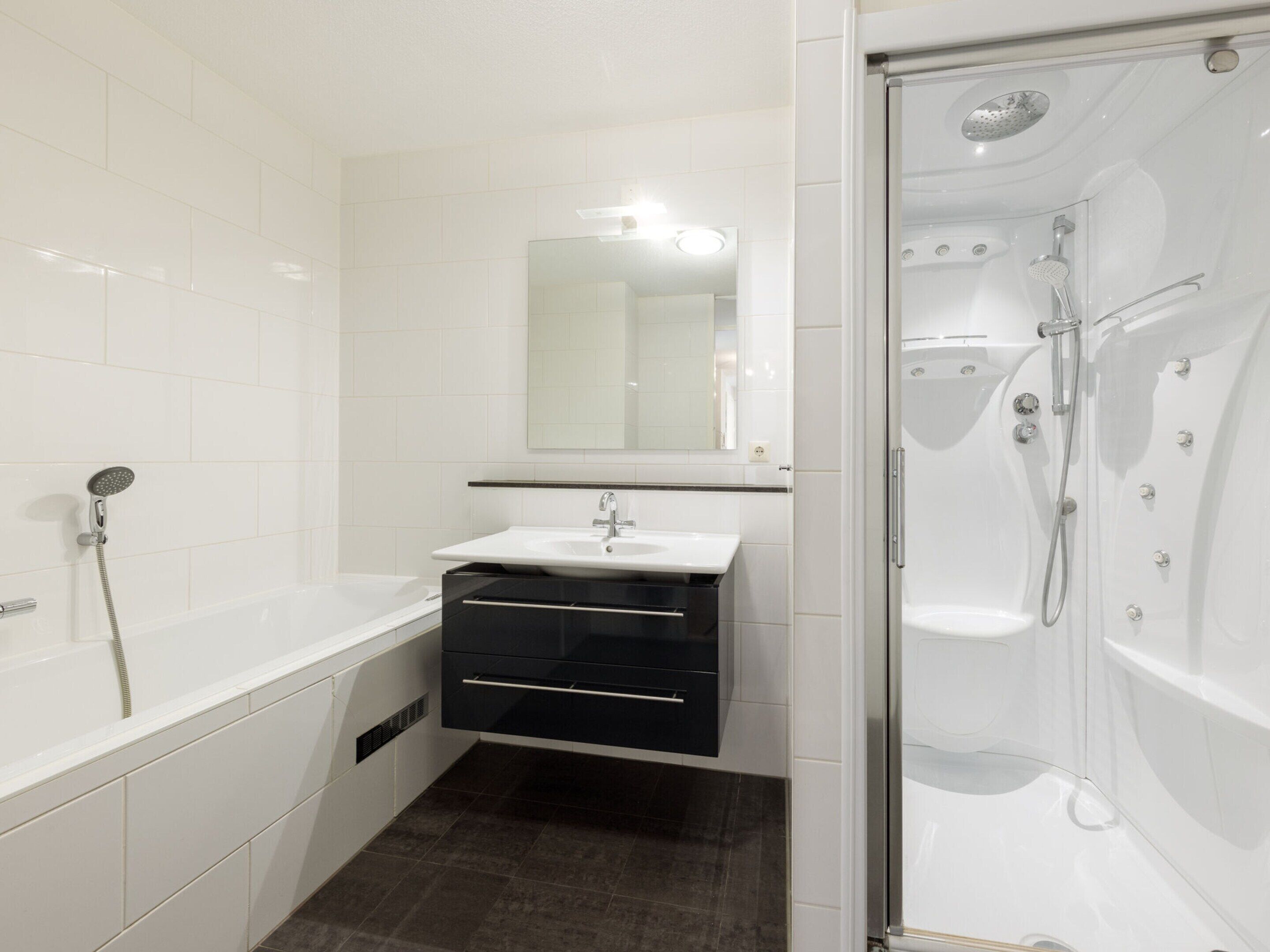 A modern bathroom with a bathtub, a shower, and a sink with a mirror above it.