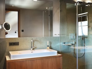 A modern bathroom with a large mirror, a sink, and a shower. - Spacious Apartment in Salzburg With Sauna (Piesendorf)