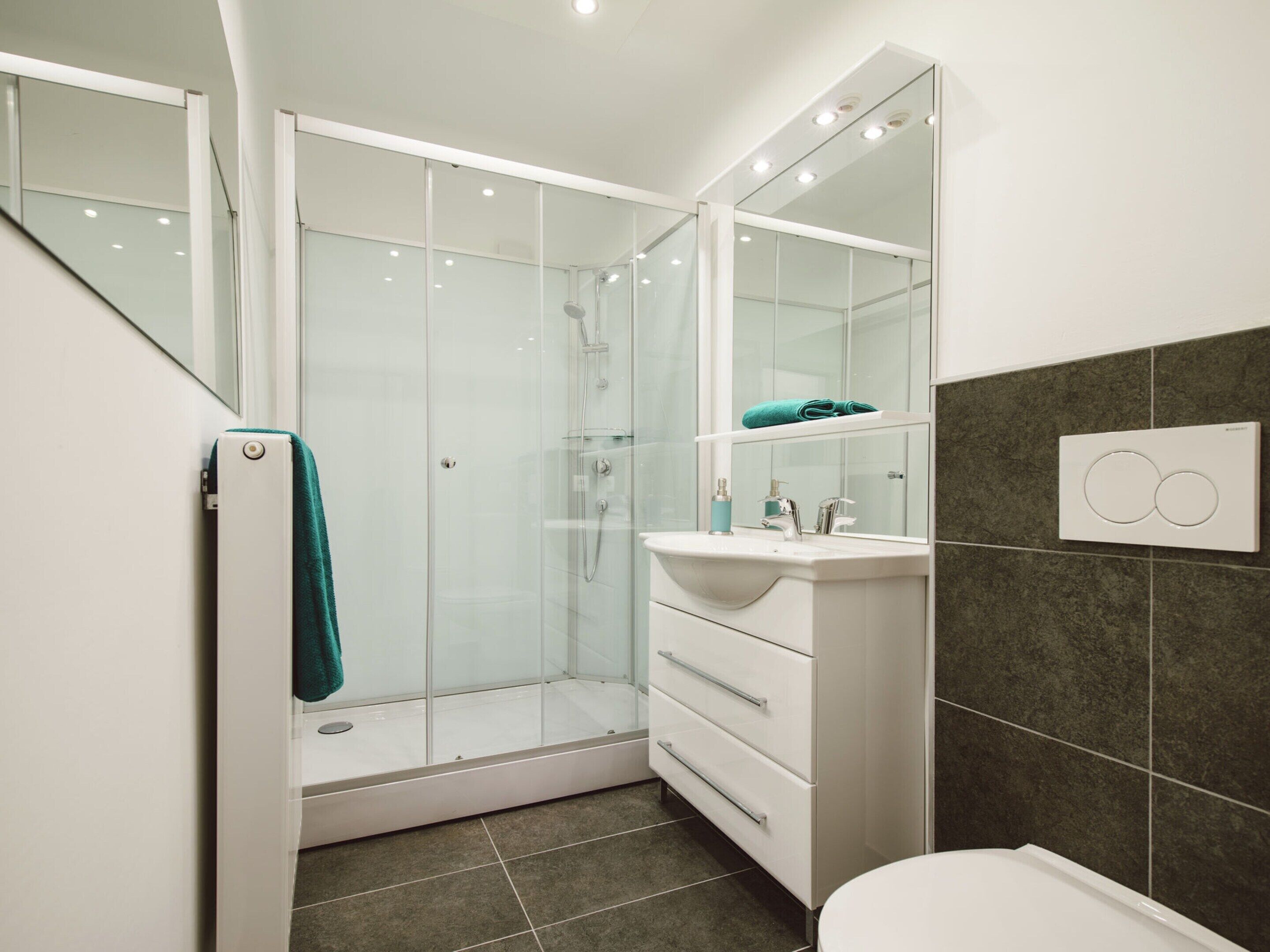 A modern bathroom with a glass shower enclosure, a white vanity with a mirror, and a toilet.