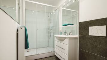 A modern bathroom with a glass shower enclosure, a white vanity with a mirror, and a toilet.