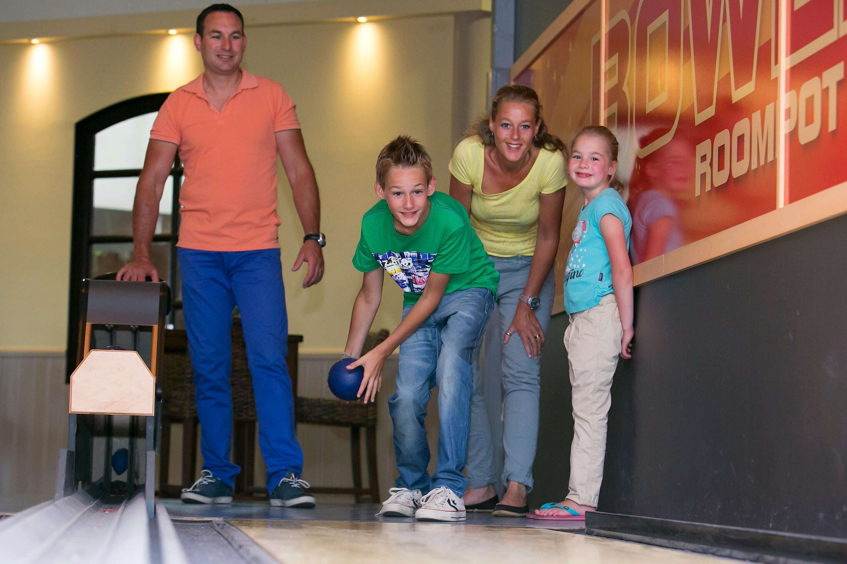 Une salle de bowling avec une piste, des quilles et une boule.