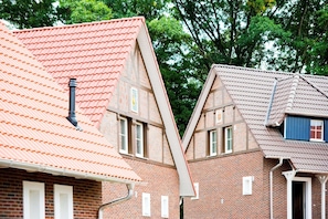 Two brick houses with red-tiled roofs and white window frames.