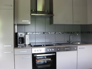 A modern kitchen with a built-in oven, a microwave, and a stainless steel sink.