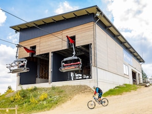 A modern building with a ski lift, a dirt path, and a cyclist. - Spacious, Modern Apartment Near the Centre (Winterberg)