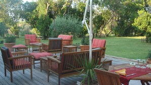 A wooden deck with outdoor furniture, including chairs and a table, surrounded by greenery. - Holiday Home in Corsica Near the Beach (Poggio-Mezzana)
