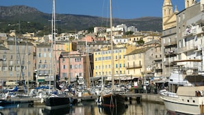 A marina with boats, colorful buildings, and a mountain in the background. - Holiday Home in Corsica Near the Beach (Poggio-Mezzana)