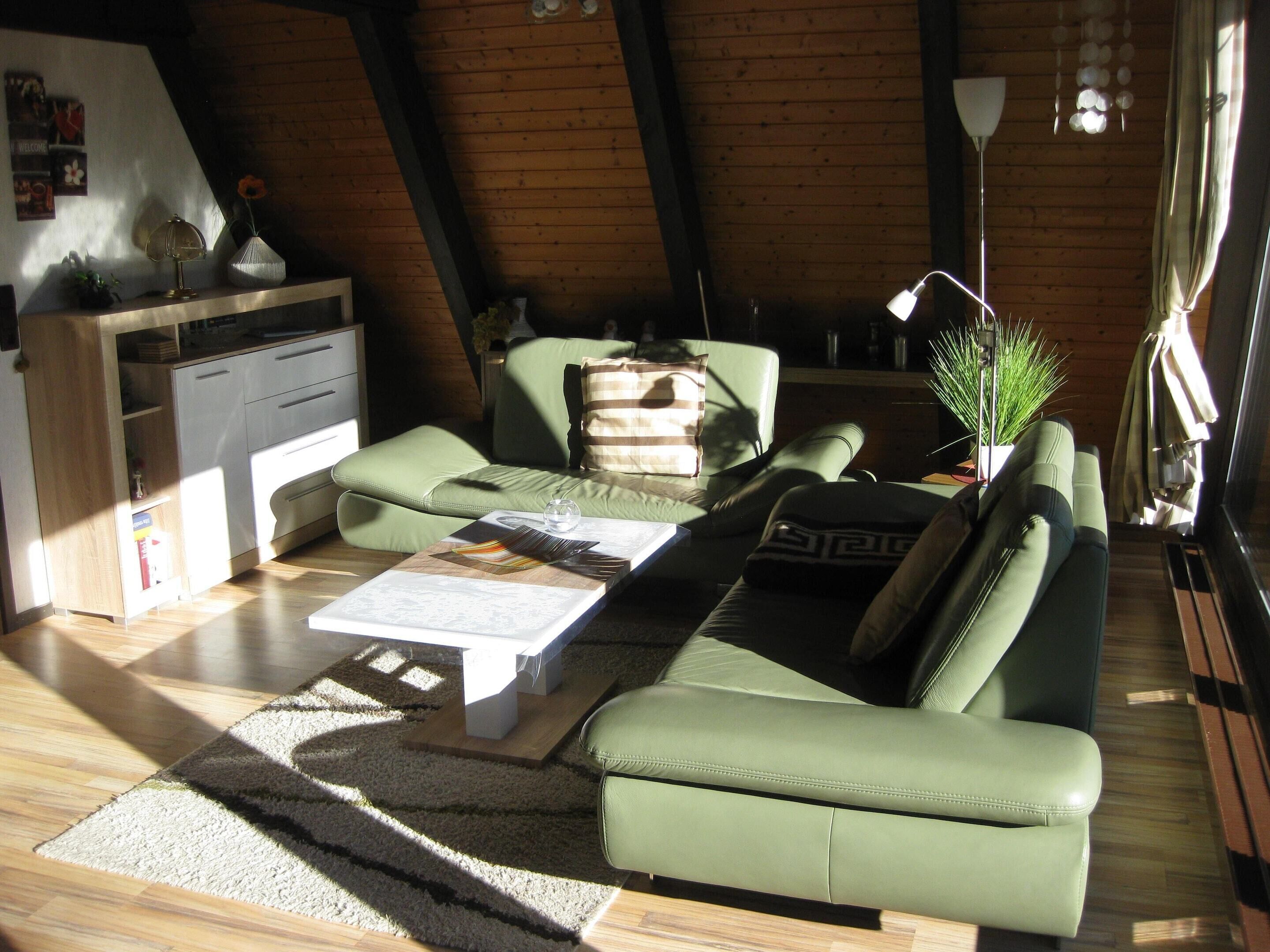 A modern living room with a green sofa, a coffee table, and a wooden ceiling.