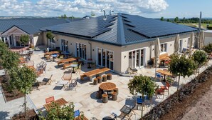 A modern building with a flat roof, large windows, and an outdoor patio area with tables and chairs. - Restyled Villa with Washing Machine near River Moselle (Ediger-Eller)