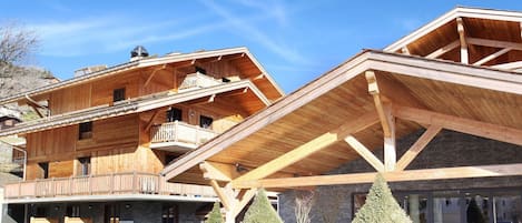 Un edificio de madera de varios pisos con balcones, un porche cubierto y macetas con plantas.
