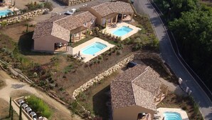 Un barrio residencial con varias casas, cada una con piscina y un muro de piedra alrededor de la propiedad.