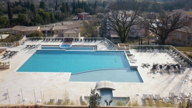 Una piscina con tumbonas y vistas del paisaje circundante.