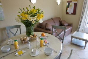 A dining table with breakfast items, a vase of flowers, and a couch in the background. - Villa in Callian With Private Pool (Callian)
