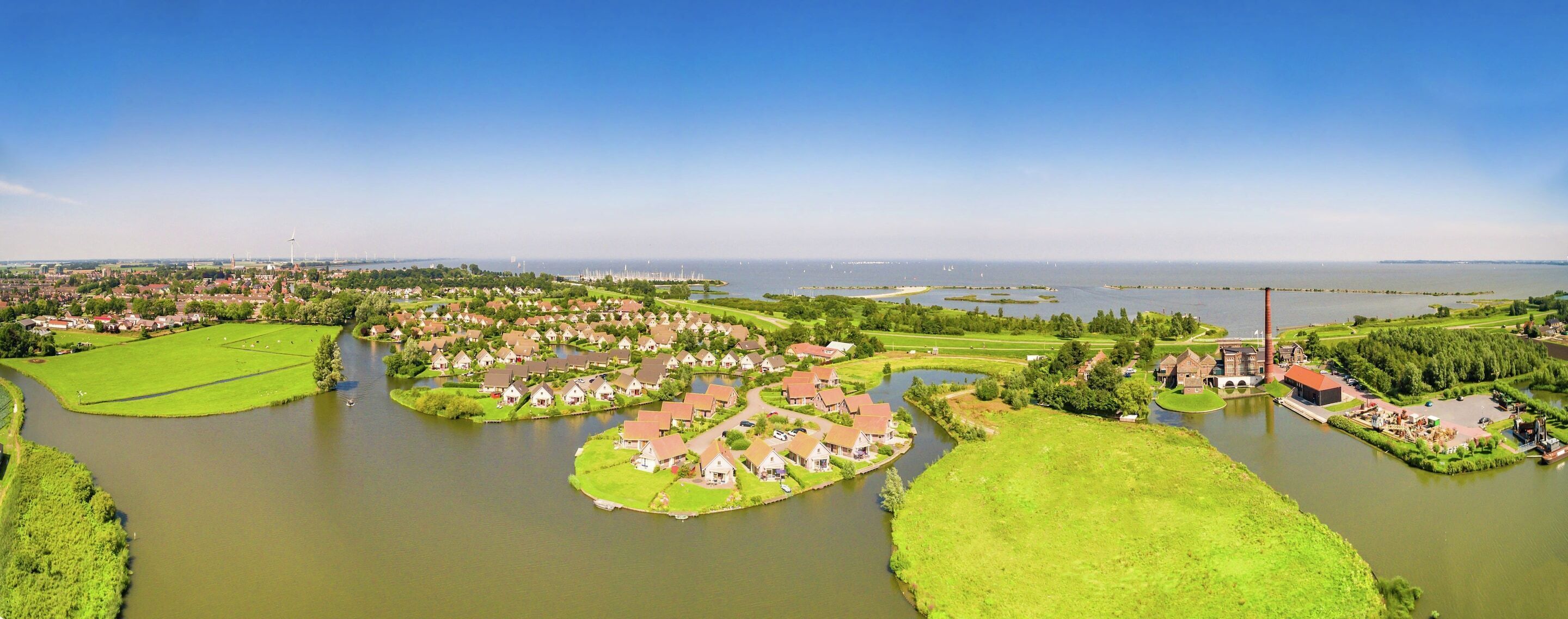 A residential area with houses arranged around a central water body, connected by pathways.