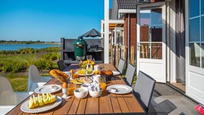 An outdoor dining area with a table set for breakfast, overlooking a body of water. - Beautiful House With Sauna Near Ijsselmeer (Medemblik)