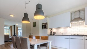 Una cocina moderna con armarios blancos, una mesa de comedor de madera y dos lámparas colgantes.