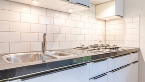 Una cocina moderna con azulejos blancos, electrodomésticos de acero inoxidable y un lavabo doble.