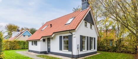 A two-story house with a red-tiled roof, white exterior walls, and a small front porch.