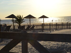 Une plage avec des parasols en bois et une clôture en bois.