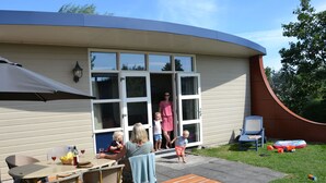 Ett hus med en uteplats, ett bord, stolar och en gräsmatta.