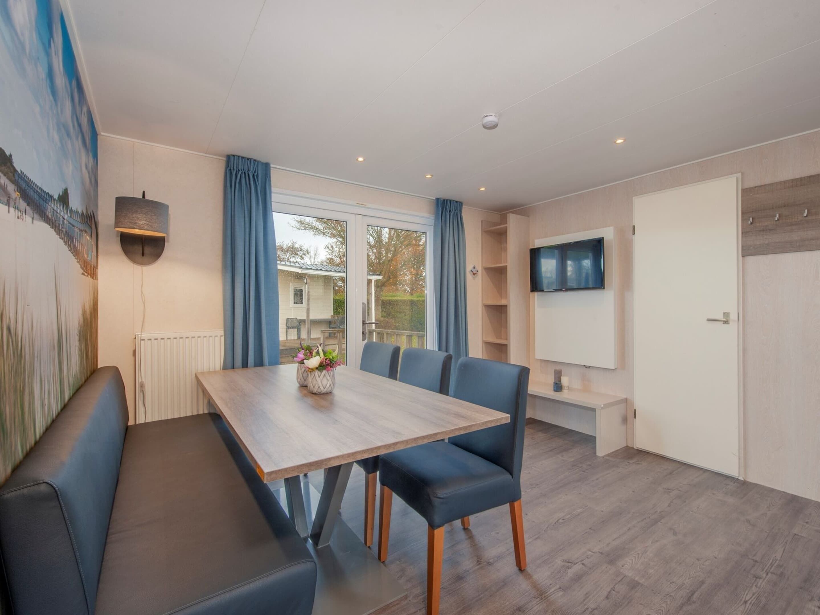 Ein moderner Essbereich mit Holztisch, blau gepolsterten Stühlen und einer Bank.