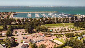 An aerial view of a marina with numerous boats docked, surrounded by residential buildings and greenery. - Chalet Near the Beach With Dishwasher (Kamperland)