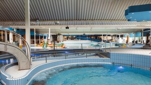 An indoor swimming pool with a slide, a children's play area, and a covered seating area. - Chalet Near the Beach With Dishwasher (Kamperland)
