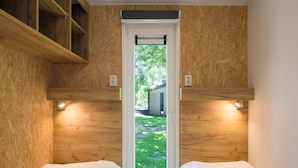 A room with two beds, wooden walls, and a window with a view of a grassy area and a building outside. - Chalet at Roompot Beach Resort Near the Coast (Kamperland)