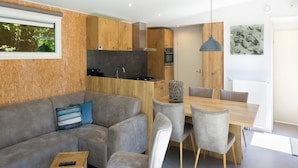 A modern living room with a grey sofa, a wooden dining table, and grey chairs. - Chalet at Roompot Beach Resort Near the Coast (Kamperland)