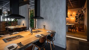 Un'area pranzo moderna con un lungo tavolo in legno, sedie nere e una griglia a incasso.