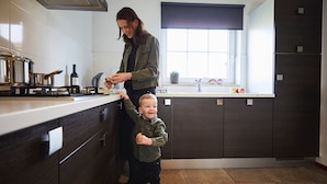 Une cuisine moderne avec des meubles en bois foncé, une cuisinière en acier inoxydable et une fenêtre offrant une belle vue.