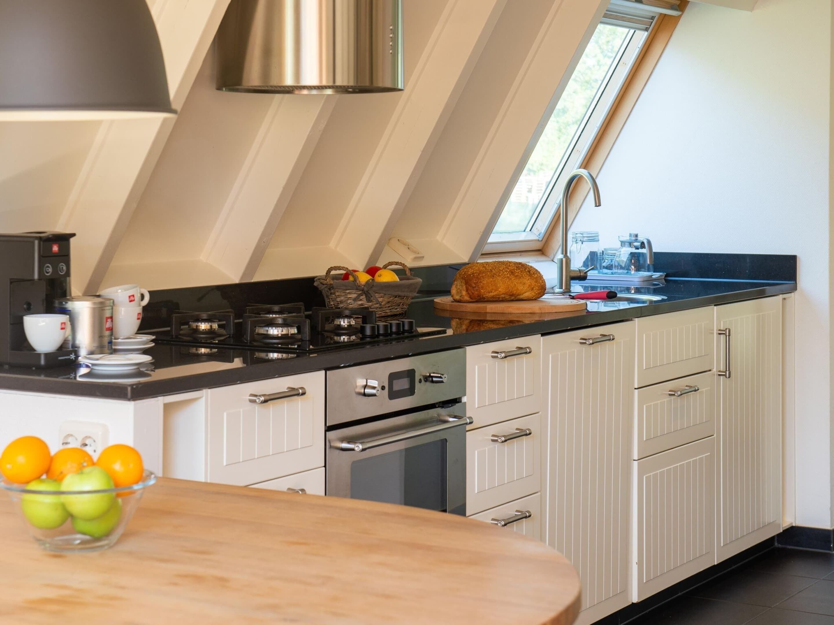 A modern kitchen with a gas stove, oven, and a window above the sink.