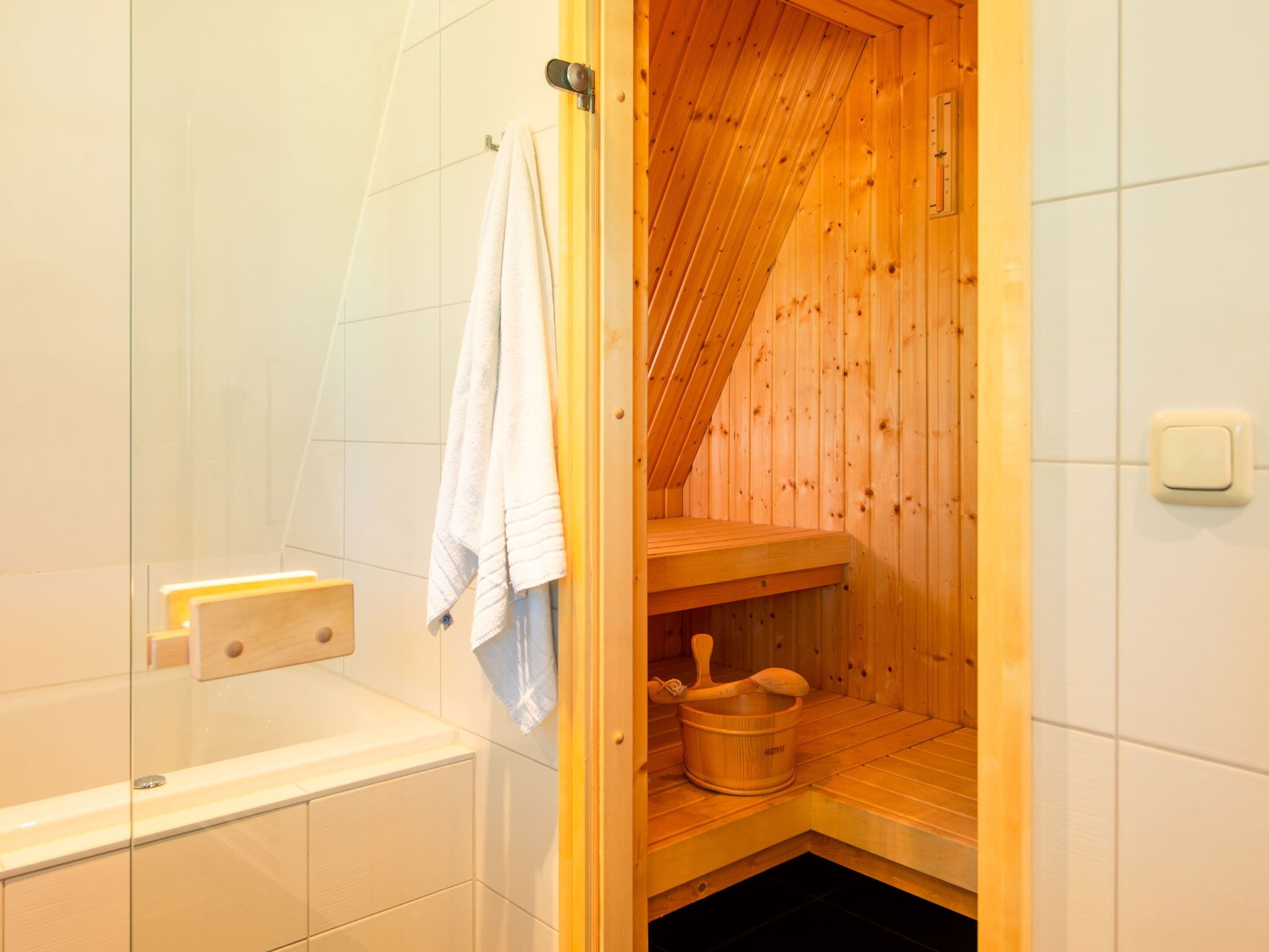 Un sauna avec des murs en bois, un banc et un bassin en pierre.
