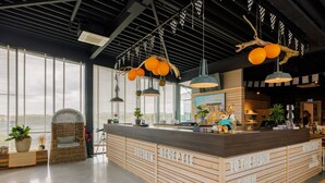 A reception area with a wooden reception desk, check-in counter, and a large window with blinds. - Bloemendaal Beach Escape (Overveen)